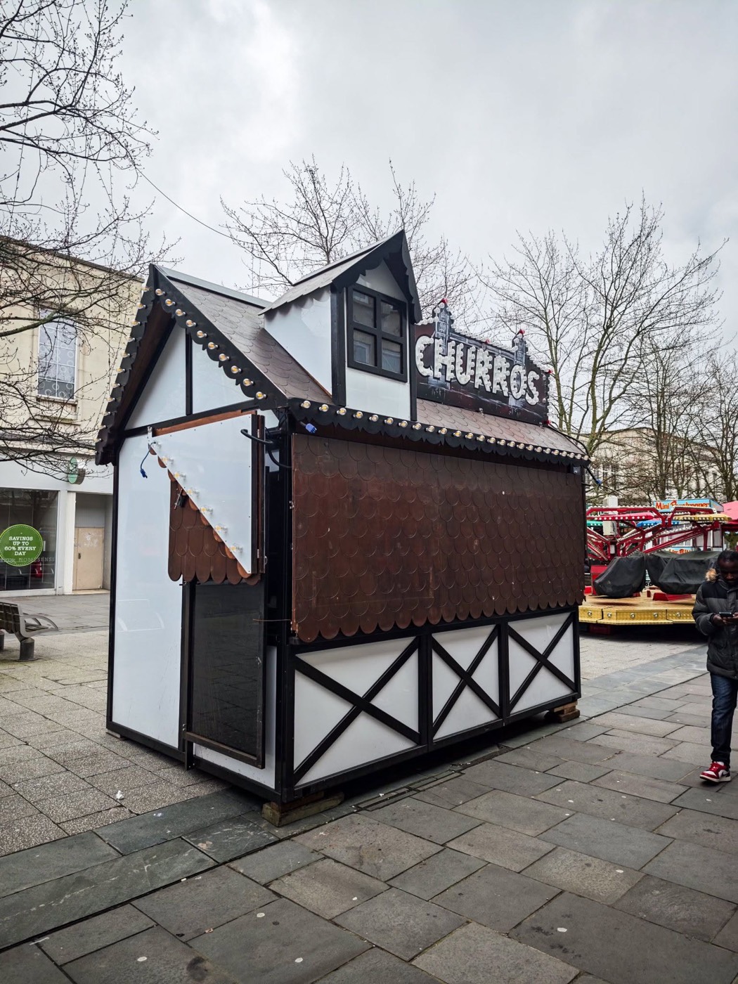 A single closed churros chalet on a grey day with bare trees behind