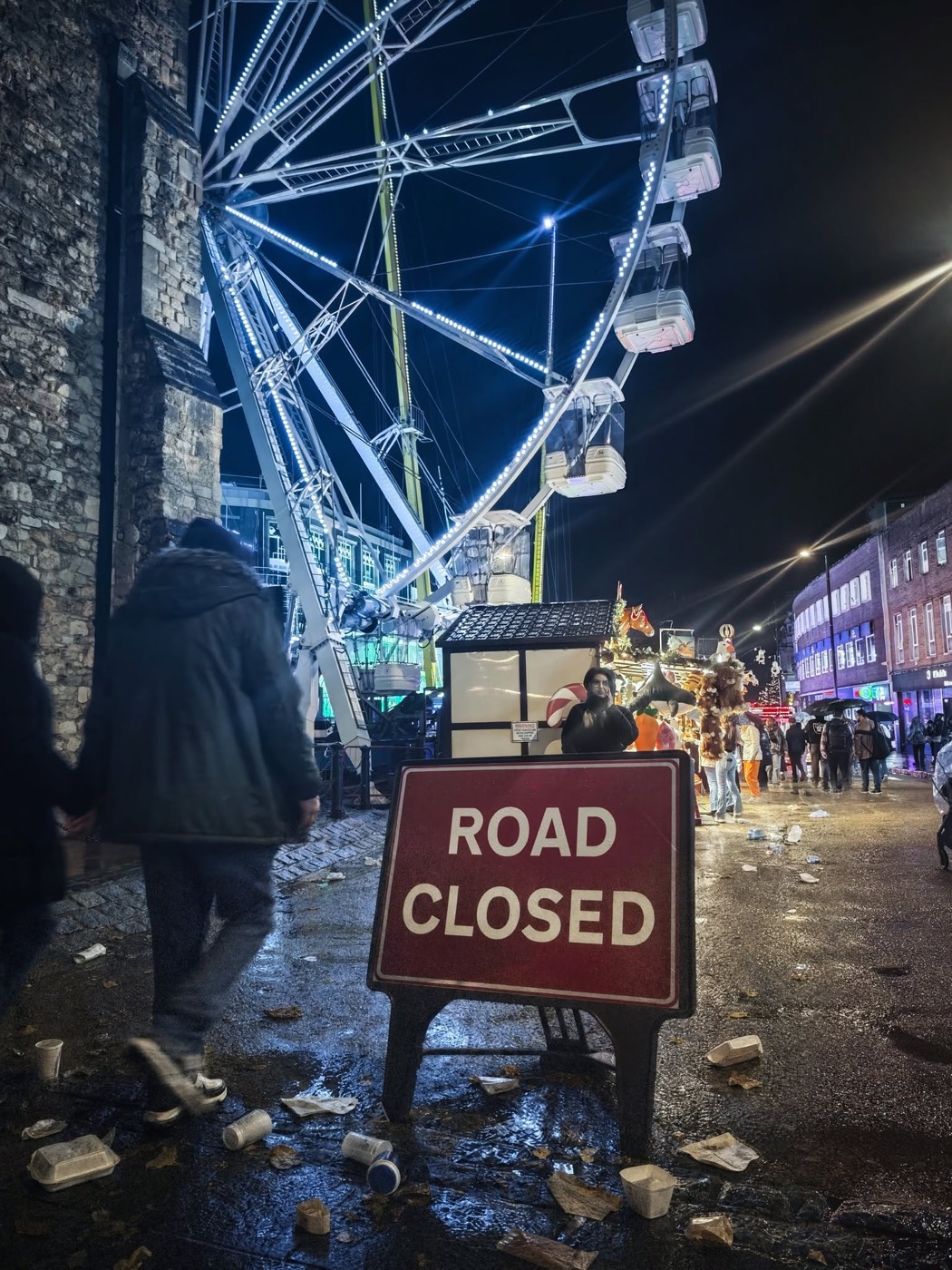 Above Bar Street at night, closed to traffic, with a ferris wheel and a Road Closed sign